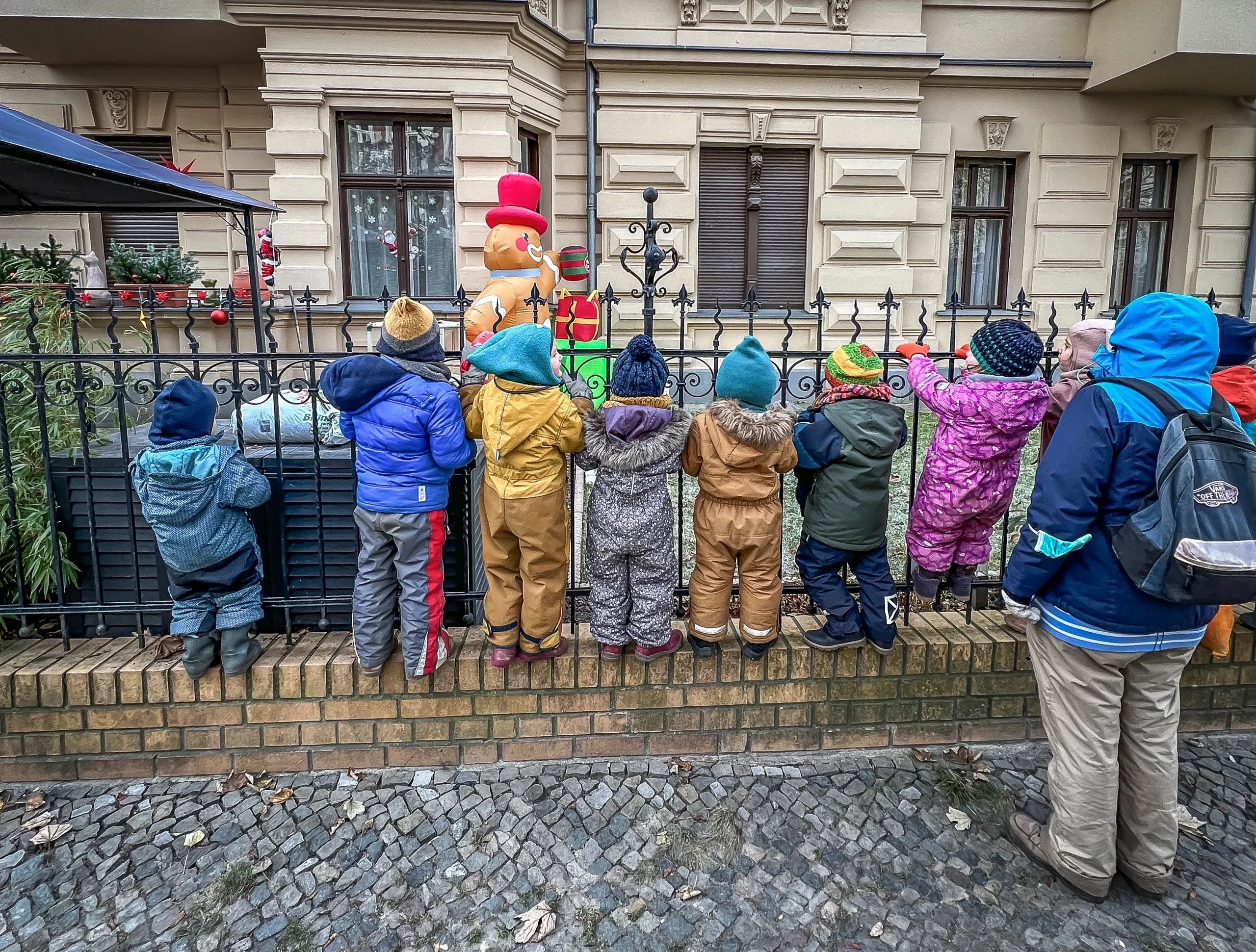 Kinder stehen am Zaun und schauen in einen Garten